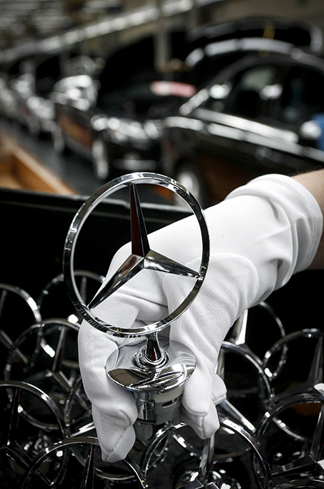 A worker of the Mercedes-Benz car factory in Bremen in northern Germany, takes an emblem for a C Class car, December 14, 2007. The new Mercedes-Benz C Class estate is produced exclusively in Bremen.   REUTERS/Focke Strangmann  (GERMANY)
